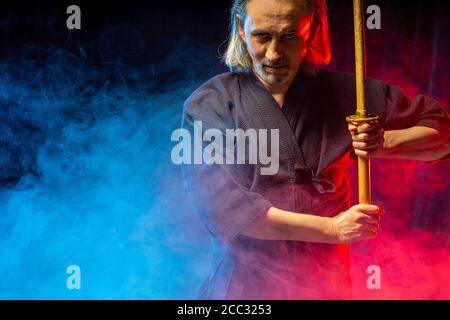 combattente caucasico forte in abiti tradizionali. arti marziali giapponesi, guerriero di combattimento, samurai concetto. uso di shinai per combattere Foto Stock