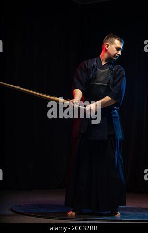 Combattente caucasico maschile kendo in stile tradizionale giapponese di abbigliamento, armatura protettiva, utilizzando shinai. Pratica lotta isolato Foto Stock