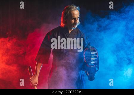combattente caucasico forte in abiti tradizionali. arti marziali giapponesi, guerriero di combattimento, samurai concetto. uso di shinai per combattere Foto Stock