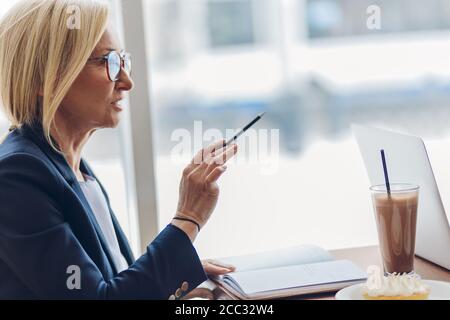 psicologa di talento che consulta un cliente al bar. primo piano vista laterale foto. copia spazio. vecchia donna intelligente che istruisce un cliente Foto Stock