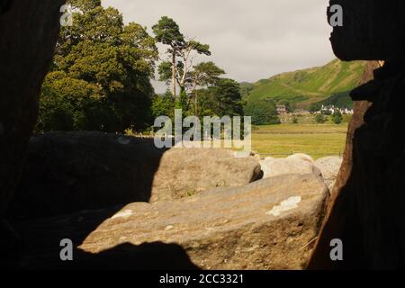 Una vista che guarda su Kilmartin Glen, dall'interno di una delle camere di sepoltura, fino alla chiesa di Kilmartin e l'hotel con Barr Mor che si alza alle spalle Foto Stock