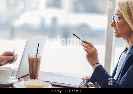 venditore femminile che presenta il suo bene alla gente. primo piano vista laterale ritagliato foto Foto Stock