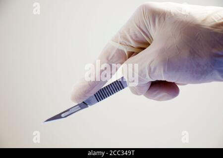 Coltello chirurgico che tiene sullo sfondo bianco, studio shot. Attrezzatura di funzionamento. Foto Stock