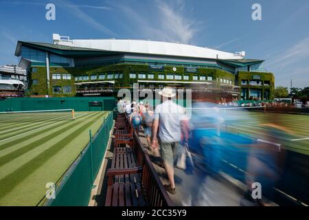 I fan che camminano per il centro di campo si sfuggono al movimento, nei terreni dell'All England Lawn Tennis Club, sede dei Wimbledon Championships Foto Stock