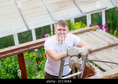 Un uomo si alza sulle scale, riposandosi e sorridendo alla telecamera Foto Stock