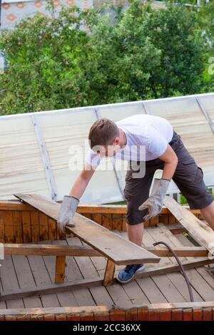 smontaggio del tetto. Il lavoratore rimuove le vecchie tavole Foto Stock