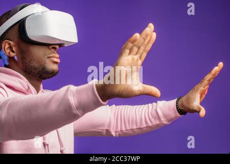 Casualmente vestito americano africano maschio home designer che lavora nel suo progetto utilizzando occhiali per realtà virtuale compiendo gesti con le mani come se egli gestire Foto Stock