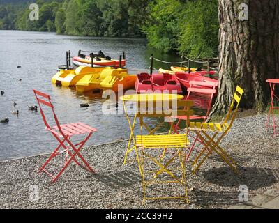 Colorata scena di rosso e giallo tavolo da bistrot e sedie per abbinare i pedalos a noleggio presso la Pitlochry Boating Station sul Loch Faskally. Foto Stock