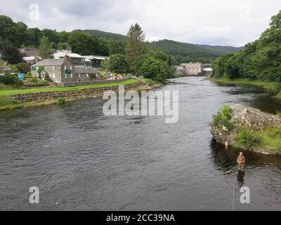 Vista dal ponte sospeso di Port-na-Craig sul fiume Tummel verso il Pitlochry Festival Theatre, con un pescatore in primo piano. Foto Stock