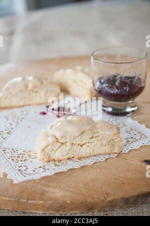 Focaccine smaltate fatte in casa appena sfornate con scorza d'arancia e confettura di lamponi. Pizzo in modo pizzo. Riprese in studio al coperto. Foto Stock