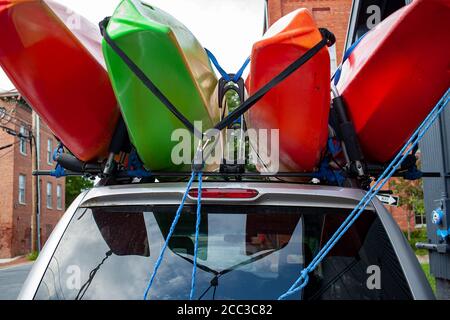 Primo piano, profondità di campo poco profonda, immagine di vista dell'occhio di bug di quattro kayak di dimensioni complete di colore rosso e verde caricati sulla parte superiore di un'auto SUV utilizzando una combinazione o Foto Stock