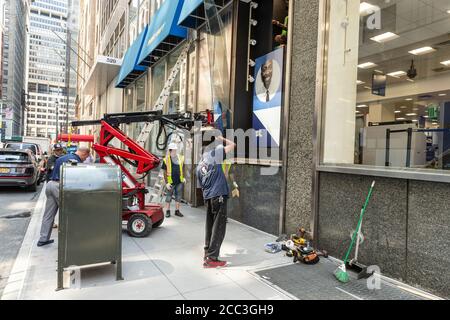 New York, NY - 17 agosto 2020: Lavoratori da Olympic Glass e Metal Inc installazione nuova finestra sul negozio Best Buy sulla 5th Avenue dopo che vecchio è stato rotto da looters Foto Stock
