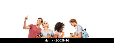 Foto panoramica di studenti multietnici che prendono selfie e tengono libri con caffè da isolare su bianco Foto Stock