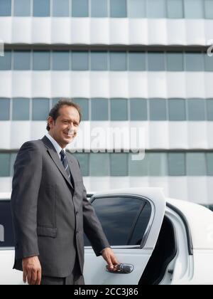 Ritratto di uomo che lavora come conducente in limousine bianca Foto Stock