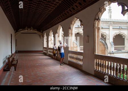 Toledo, Spagna. Agosto 2020. Una giovane coppia turistica che indossa la maschera per evitare Covid-19 scatta foto e fissa saldamente al chiostro del Monast Foto Stock