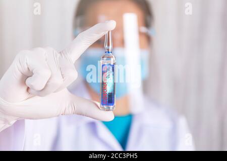 Vaccino del coronavirus Covid-19. Primo piano le mani dello scienziato mostrano Covid-19 vaccino in fiala di vetro. Le mani del medico indossano il guanto di lattice che regge Covid-19 Vaci Foto Stock