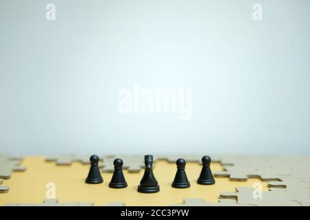Foto concettuale della strategia aziendale - una linea di cavallo pezzi di scacchi nel mezzo di un esercito e jigsaw puzzle Foto Stock