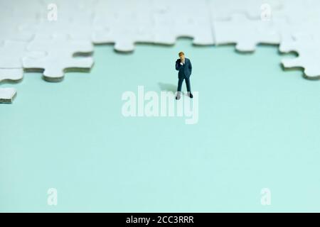 Business strategy Conceptual photo - uomo d'affari in miniatura pensare davanti di puzzle Foto Stock