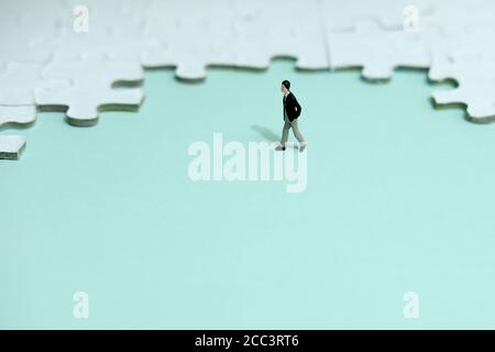Business strategy Conceptual photo - uomo d'affari in miniatura che cammina di fronte di puzzle Foto Stock