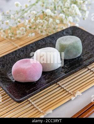 Diversi sapori di Mochi su una piastra rettangolare nera e. Baby Breath Fiori sfondo Blur Foto Stock