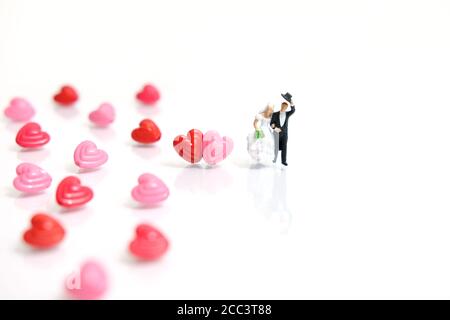Fotografia in miniatura di persone per giorno di valentine, sposa e sposo con forma del cuore e perle di parole d'amore su sfondo bianco lucido Foto Stock