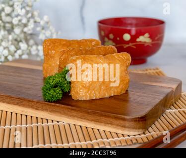 Inarisushi su una tavola di legno con sfondo di zuppa di miso sfocato Foto Stock
