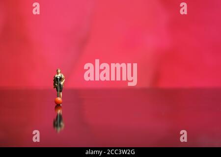Fotografia in miniatura - elegante cantante femminile che canta su rosso lucido pavimento lucido Foto Stock