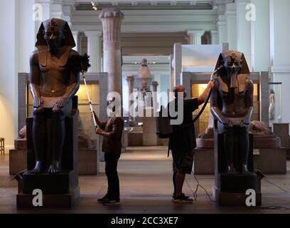 I manager della collezione Alex Truscott (a sinistra) e Evan York spolverano le statue di Amenhotep III (circa 1390-1352 a.C.), nella Egyptian Sculpture Gallery al British Museum di Londra, mentre si preparano a riaprire al pubblico il 27 agosto dopo il blocco del coronavirus. Prima della riapertura, il British Museum ha avviato il più grande programma di pulizia individuale degli ultimi decenni. Foto Stock