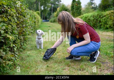 18 agosto 2020, Amburgo: Una giovane donna raccoglie l'escrezione del suo Havanese con un sacco di cane. Esercizio sufficiente, mancanza di mantenimento della catena e divieto di mostrare animali con determinate caratteristiche - con norme più severe il Ministero federale dell'agricoltura vuole garantire un allevamento di cani appropriato per le specie. Gli attivisti del benessere degli animali e i proprietari di cani gradiscono l'iniziativa - anche l'obbligo previsto di garantire il cane almeno due volte al giorno per un totale di almeno un'ora di esercizio all'aperto fuori di un allevamento. La misura è stata commentata nei social media come un "dovere di escursionista" in parte maliziosamente. PH Foto Stock