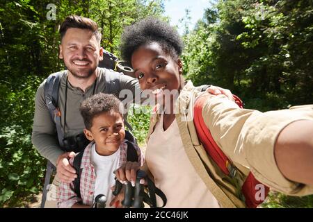 Ritratto di felice famiglia di tre facendo selfie ritratto sopra il telefono cellulare durante le escursioni Foto Stock