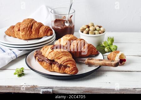 Croissant appena sfornati con crema di cioccolato su un tavolo bianco rustico. Foto Stock