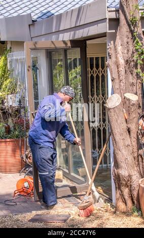 Alberton, Sudafrica - un lavoratore migrante nero fa lavoro non specializzato in un giardino residenziale per guadagnare un'immagine vivente in formato verticale Foto Stock