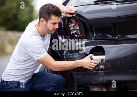 Infelice driver maschio che esamina l'auto danneggiata dopo un incidente Foto Stock