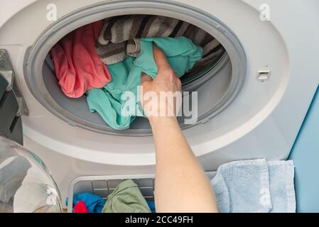 le mani della donna toglie la biancheria dalla lavatrice. la donna mette i vestiti in una lavatrice. Foto Stock