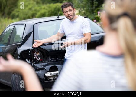 Uomini e donne che discutono sui danni alle vetture dopo Incidente Foto Stock