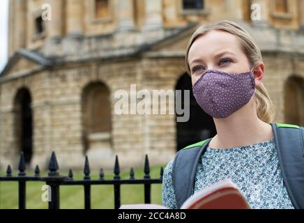 Donna turistica in vacanza indossare maschera viso durante Covid-19 Pandemic Libro della Guida Turistica di Reading a Oxford Regno Unito Foto Stock