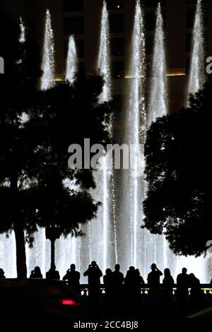 Scena notturna con sagome di persone che ammirano lo spettacolo delle fontane Bellagio a Las Vegas, Nevada Foto Stock