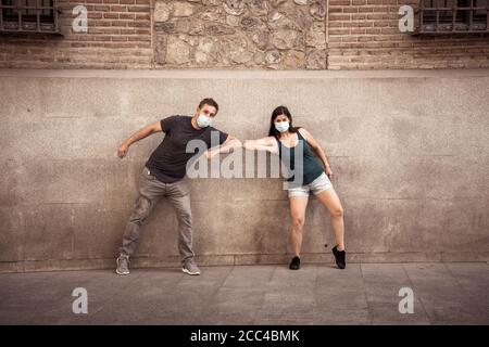 Il nuovo stile normale e di saluto. L'uomo e la donna scuotono i gomiti o i piedi mantenendo la distanza sociale per evitare che Coronavirus si diffonda. COVID-19 focolaio e d Foto Stock