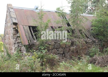 Casa colonica in pietra derelict costruita con tetto in metallo Foto Stock