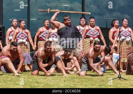 Maori neozelandese uomini e donne di un gruppo kapa haka (danza tradizionale). L'uomo centrale detiene un taiaha, o lancia. Tauranga, NZ, 2/6/2019 Foto Stock