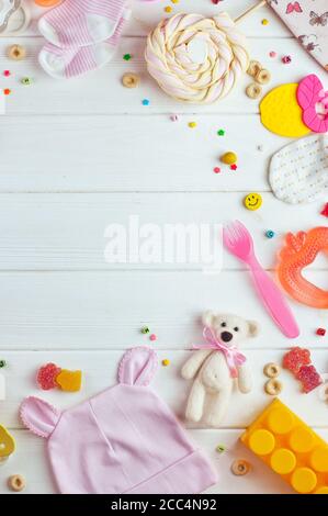 Vestiti per bambini, accessori e giocattoli su sfondo bianco di legno Foto Stock