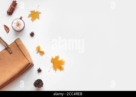 Composizione autunnale - latte di spezie di zucca, borsa in pelle scamosciata, foglie autunnali su sfondo bianco, posa piatta, vista dall'alto, spazio di copia. Concetto di autunno stagionale con c Foto Stock