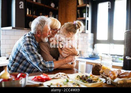 Felici i nonni con i nipoti facendo colazione in cucina Foto Stock