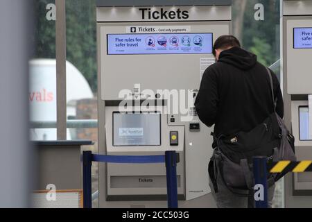 Uomo in piedi davanti a un distributore automatico di biglietti del treno Presso la stazione Haymarket di Edimburgo Foto Stock