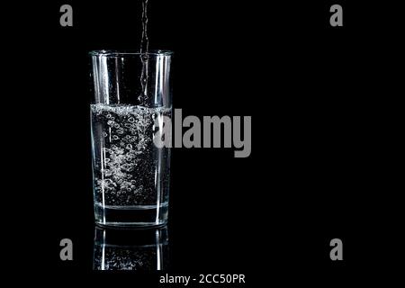 Versare acqua in vetro su fondo nero Foto Stock