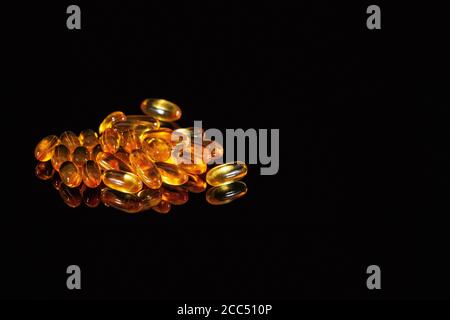 Capsule medicinali arancioni su sfondo nero Foto Stock