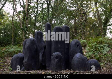 'Black Mound' di David Nash, RA, una potente collezione di forme di quercia in un huddle scolpito: Tremenheere Sculpture Garden, Penzance, Cornovaglia Foto Stock