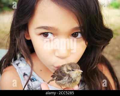 Primo piano di una bambina che baciava uno passero Foto Stock