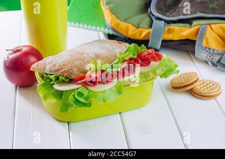 Primo piano del pranzo al sacco con sandwich vicino a mela, biscotti, thermos tazza e zaino Foto Stock