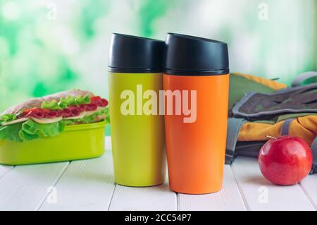 Thermos thermos colore tazze vicino pranzo scatola e zaino Foto Stock